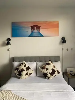 a bed with two pillows and a painting on the wall at Nature Inspired Affordable Rooms in F RESIDENCE near Edsa Shaw Pasig Megamall Shangrila and MRT in Manila