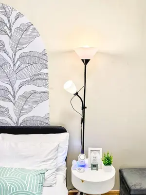 a lamp on a side table next to a bed at Sunshine 100 Cozy Mandaluyong Studio Near BGC in Manila