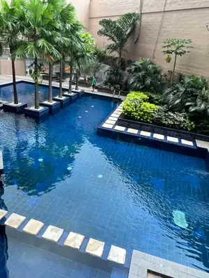 a swimming pool in a building with palm trees at Sunshine 100 Cozy Mandaluyong Studio Near BGC in Manila