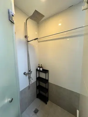 a bathroom with a shower and a black shelf at Sunshine 100 Cozy Mandaluyong Studio Near BGC in Manila