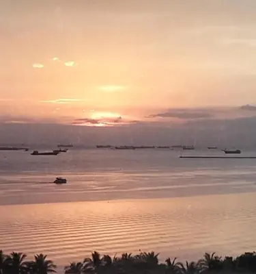 a sunset over the ocean with boats in the water at Chic Haven in Manila