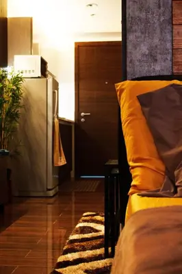 a room with a bed and a refrigerator and a door at The Brick and Wood Suite Industrial Haven in Makati in Manila