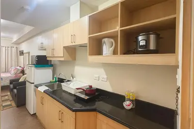 a kitchen with a black counter top and wooden cabinets at La Verti Residences Unit 1420 I Skyline Views & Luxe Stay Near MOA in Manila