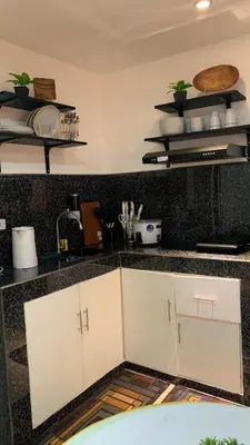 a kitchen with white cabinets and a black counter top at Modern Studio near MOA, Airport & Heart of Pasay in Manila