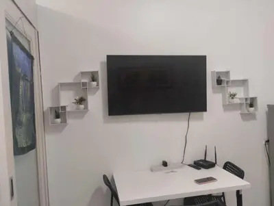 a room with a desk with a television on a wall at Bini Comfort room in Manila