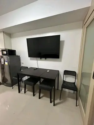 a living room with a table and chairs and a flat screen tv at Bini Comfort room in Manila