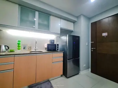 a kitchen with wooden cabinets and a stainless steel refrigerator at LARGE One Bedroom Unit In Uptown BGC in Manila