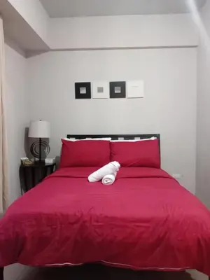a red bed with a white pillow on top of it at Cozy Jen 150newport Boulevard condotel in Manila