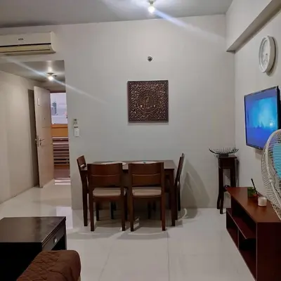 a living room with a table and chairs and a television at Cozy Jen 150newport Boulevard condotel in Manila