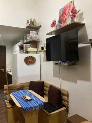a living room with a table and a flat screen tv at Rustic condo in Makati CBD in Manila