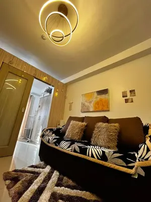 a couch in a living room with a chandelier at Affordable Condo staycation near MOA ,NAIA & Airport 4 GUESTS WIFI,NETFLIX,POOL in Manila