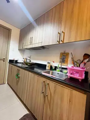 a kitchen with wooden cabinets and a sink at Affordable Condo staycation near MOA ,NAIA & Airport 4 GUESTS WIFI,NETFLIX,POOL in Manila