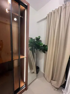 a glass cabinet with a potted plant next to a curtain at Snuggle Suites in Manila