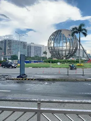 a large metal globe in a parking lot with buildings at Snuggle Suites in Manila