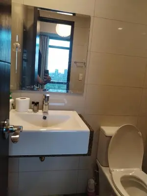 a bathroom with a sink and a toilet and a mirror at Near MOA 3 pax unit in Gentry Manor in Manila