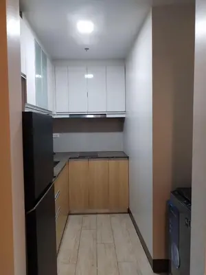a kitchen with white cabinets and a black refrigerator at Near MOA 3 pax unit in Gentry Manor in Manila