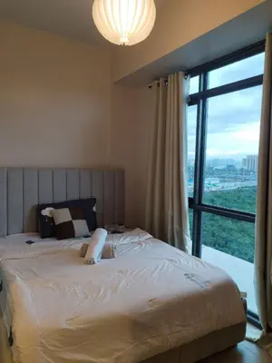 a bedroom with a large bed with a large window at Near MOA 3 pax unit in Gentry Manor in Manila