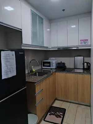 a kitchen with white cabinets and a black refrigerator at Near MOA 3 pax unit in Gentry Manor in Manila