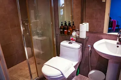 a bathroom with a shower and a toilet and a sink at Snug Stay in Gramercy Makati with City Skyline View! in Manila