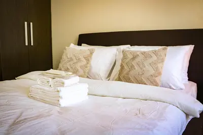 a bed with a pile of towels and books on it at Snug Stay in Gramercy Makati with City Skyline View! in Manila