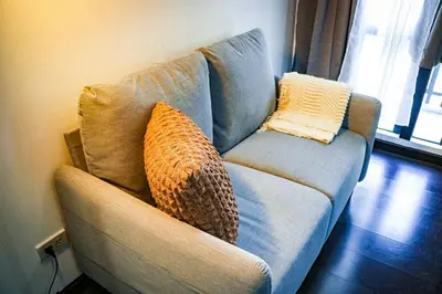 a couch with two pillows on it in a living room at Snug Stay in Gramercy Makati with City Skyline View! in Manila