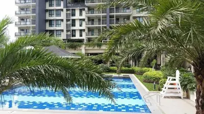 a swimming pool with palm trees and a building at NEW 2BR Family Home with FREE Parking & Fiber Wi-Fi in Manila
