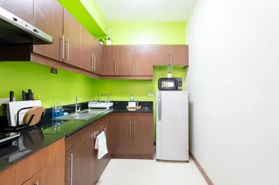 a kitchen with wooden cabinets and a white refrigerator at NEW 2BR Family Home with FREE Parking & Fiber Wi-Fi in Manila