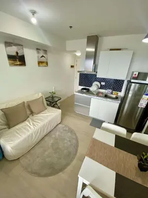 a living room with a white couch and a kitchen at The Dream Den Staycation in Manila
