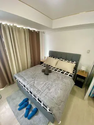 a bedroom with a bed with blue slippers on the floor at The Dream Den Staycation in Manila