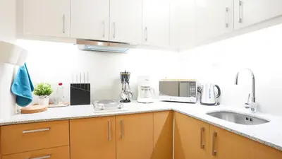 a kitchen with white cabinets and a sink at Best 1BR in Uptown BGC - Near Mitsukoshi & Malls in Manila