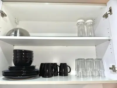 a shelf with plates and glasses in a kitchen at Comfy Makati Condo Wifi, Netflix and Disney in Manila