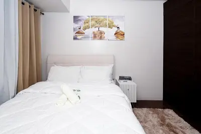 a bedroom with a white bed with two towels on it at Condo in Makati Staycation in Manila