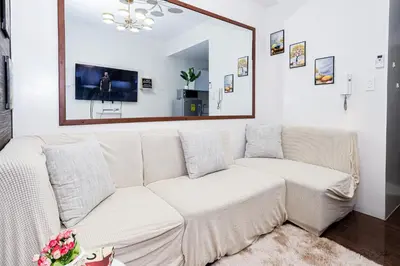a white couch in a living room with a mirror at Condo in Makati Staycation in Manila
