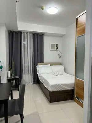 a bedroom with a bed and a desk and a window at Eve's Den in Manila