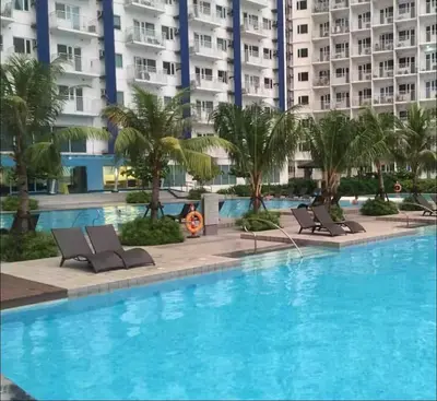 a large swimming pool with lounge chairs in front of a building at Luxury in the Makati Skyline in Manila