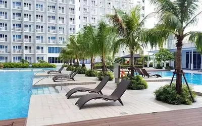 a pool with chairs and palm trees and a building at Luxury in the Makati Skyline in Manila