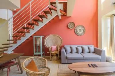 a living room with a couch and a staircase at StayHere 3BR Penthouse Knightsbridge Makati in Manila