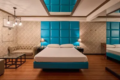 a bedroom with blue walls and a bed and a couch at Victoria Court Hillcrest in Manila