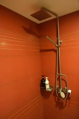 a shower in a bathroom with orange walls at Luxury Condo at Forbeswood Parklane The Fort BGC in Manila