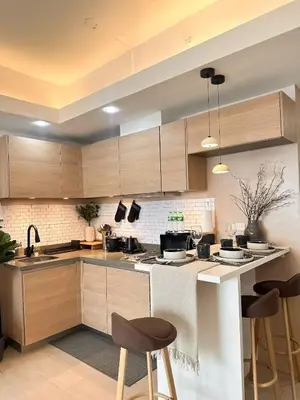 a kitchen with wooden cabinets and a counter with stools at Exquisite Japandi at Venice with Grand Canal view in Manila