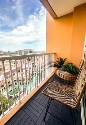 a balcony with a rattan chair and a view of a city at Exquisite Japandi at Venice with Grand Canal view in Manila
