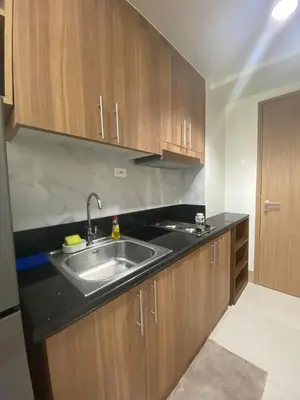 a kitchen with a sink and wooden cabinets at Happy Haven At Shore 3 Moa Pasay in Manila