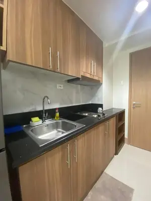 a kitchen with a sink and wooden cabinets at Happy Haven At Shore 3 Moa Pasay in Manila