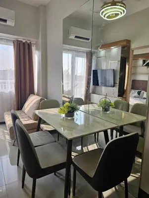 a dining table and chairs in a living room at Stunning 2 Bedroom near Airport in Manila