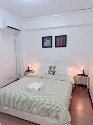a white bedroom with a large bed with two lamps at Near NAIA 3 Condo in Manila