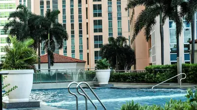 a swimming pool with palm trees and buildings at Venice Stay! Free Amenities, Steps to Grand Canal in Manila
