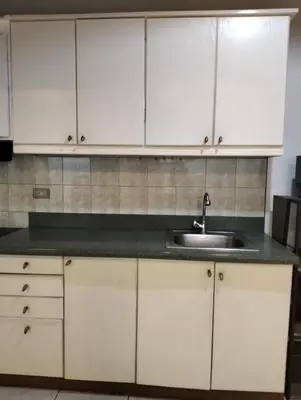 a kitchen with white cabinets and a sink at Chic Haven in Manila