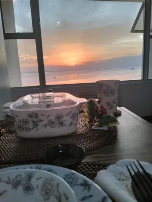 a table with plates and a bath tub with a view of the ocean at Chic Haven in Manila