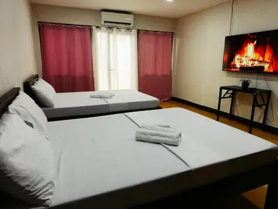 two beds in a room with a fire in the window at Manalo Resort Hotel in Tutulo