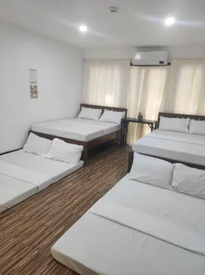 three beds in a room with wooden floors at Manalo Resort Hotel in Tutulo